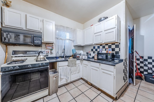 1317 N Harding Ave, Chicago, IL 60651 - kitchen with light tile patterned flooring, black microwave, white cabinetry, dark countertops, and range with gas cooktop