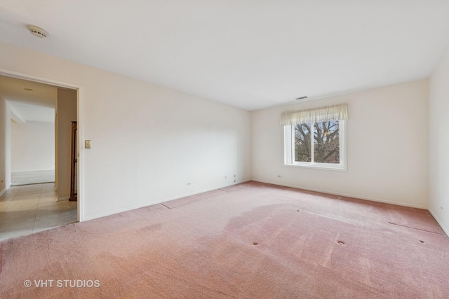 unfurnished room with carpet, visible vents, and baseboards