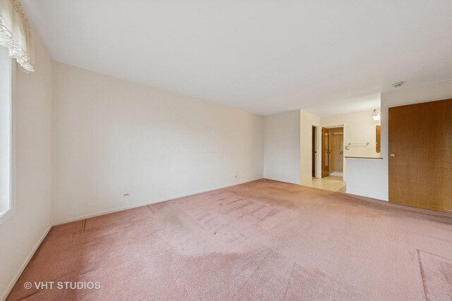 spare room with baseboards and light colored carpet