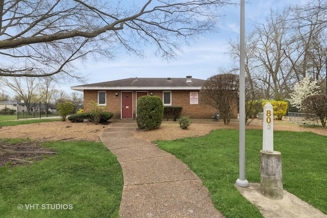 ranch-style house with brick siding, a shingled roof, a front yard, and fence