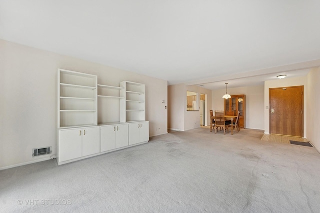 unfurnished living room featuring visible vents, light carpet, and baseboards