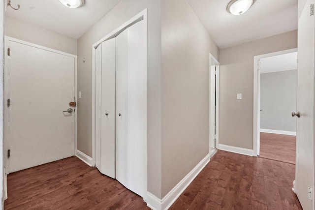 corridor with baseboards and wood finished floors