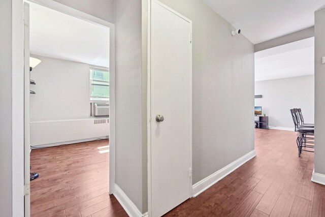 corridor featuring baseboards, cooling unit, and wood finished floors