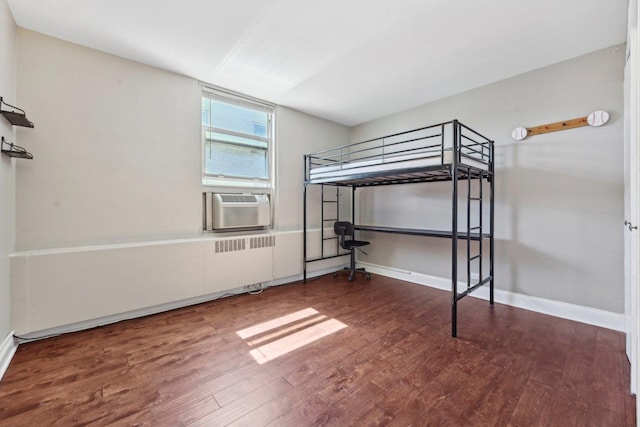 unfurnished bedroom with baseboards, cooling unit, and wood finished floors