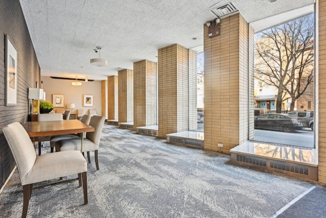 carpeted dining space featuring visible vents and wood walls