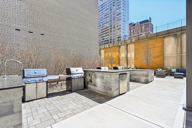 view of patio / terrace featuring grilling area, a city view, an outdoor kitchen, and a sink