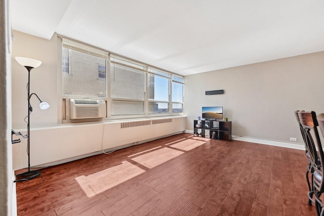 interior space featuring cooling unit, baseboards, and wood finished floors