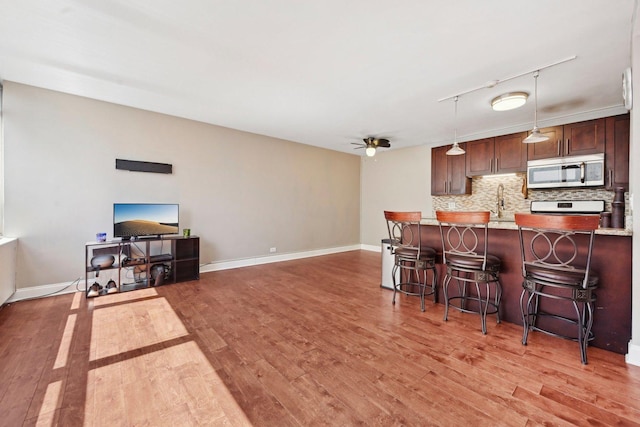 kitchen with stainless steel microwave, tasteful backsplash, a breakfast bar area, ceiling fan, and stove