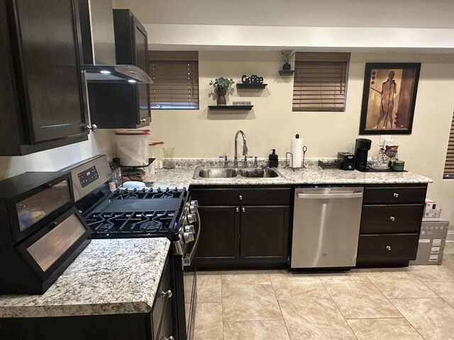 kitchen with range hood, a sink, light countertops, dark cabinetry, and stainless steel appliances