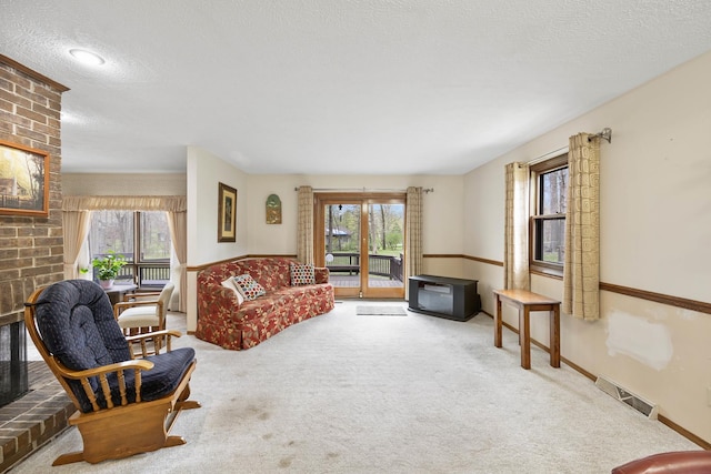 living room featuring a wealth of natural light, a brick fireplace, visible vents, and carpet