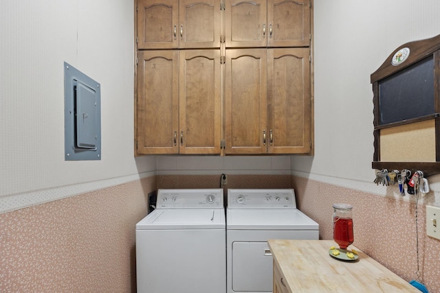 laundry area featuring electric panel, washer and clothes dryer, wallpapered walls, and cabinet space
