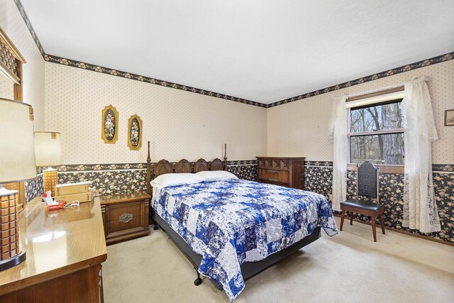 bedroom with wallpapered walls and light carpet