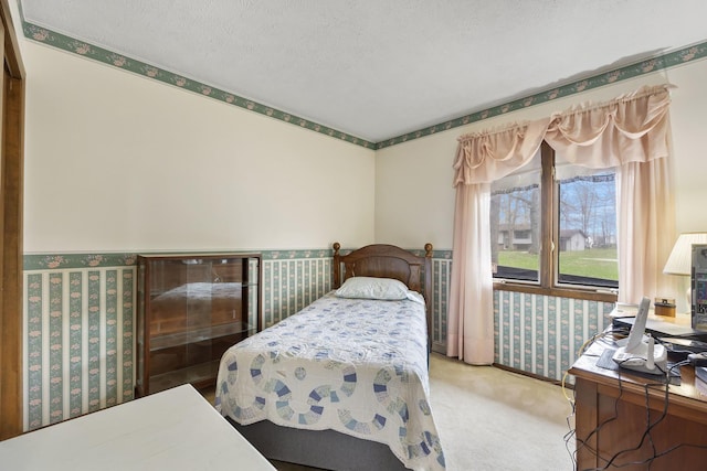 carpeted bedroom featuring wallpapered walls and a textured ceiling