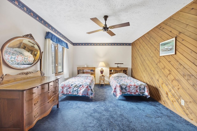 bedroom featuring a ceiling fan, carpet flooring, a textured ceiling, and wooden walls