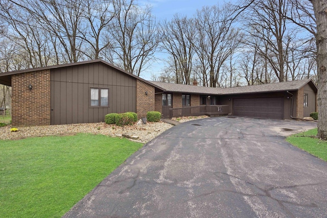 view of front of house featuring a front lawn, driveway, a chimney, brick siding, and a garage