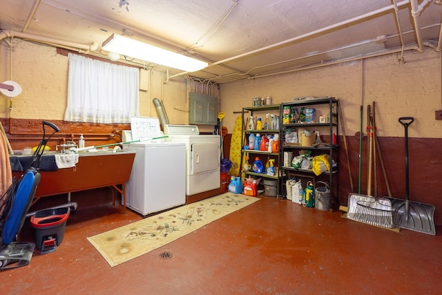 basement featuring electric panel, independent washer and dryer, and concrete block wall