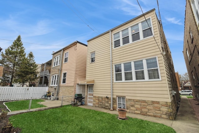 rear view of house with fence and a yard