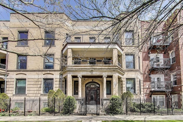 view of front facade featuring a balcony, a fenced front yard, and stone siding
