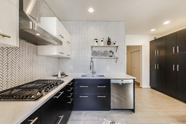 kitchen featuring stainless steel appliances, a sink, wall chimney exhaust hood, backsplash, and light countertops
