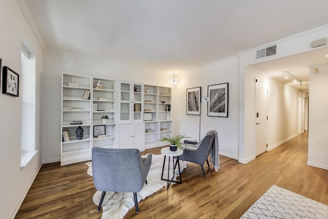 sitting room with wood finished floors, crown molding, and baseboards