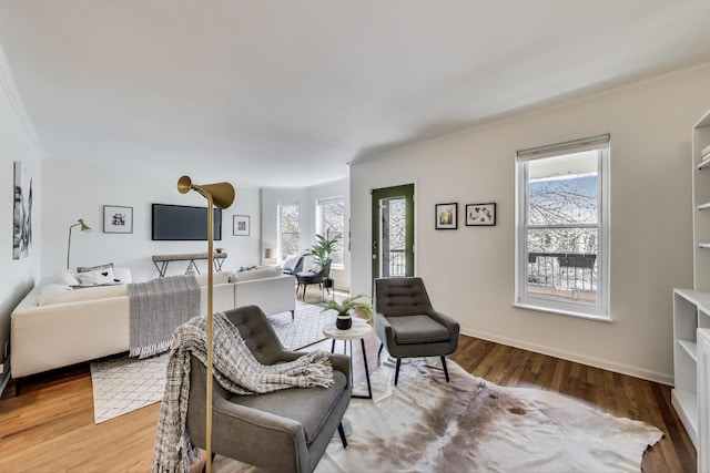 living area featuring healthy amount of natural light, crown molding, wood finished floors, and baseboards