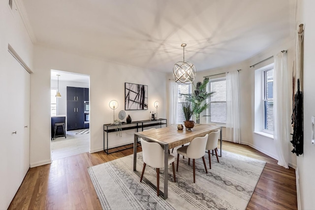 dining area featuring light wood-type flooring, a chandelier, and baseboards