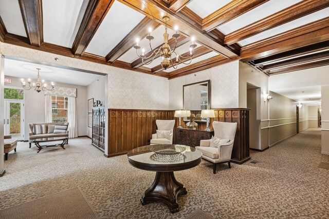 sitting room with a chandelier, carpet flooring, beam ceiling, wainscoting, and crown molding