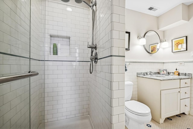 full bathroom featuring toilet, a shower stall, tile walls, a wainscoted wall, and tile patterned flooring