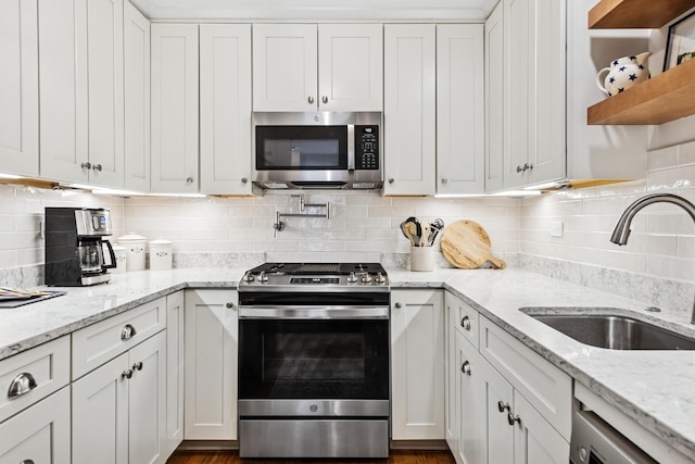 kitchen featuring appliances with stainless steel finishes, a sink, white cabinets, and decorative backsplash