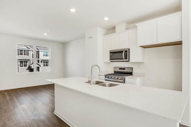 kitchen featuring dark wood-type flooring, white cabinets, appliances with stainless steel finishes, a sink, and light countertops