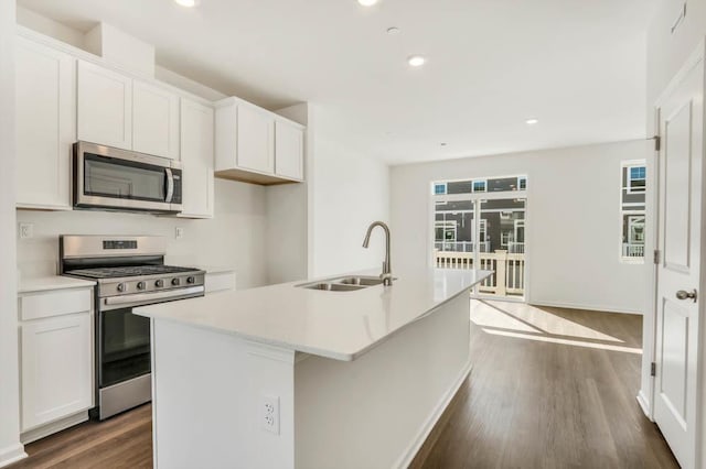 kitchen with recessed lighting, dark wood-style flooring, a sink, stainless steel appliances, and a center island with sink