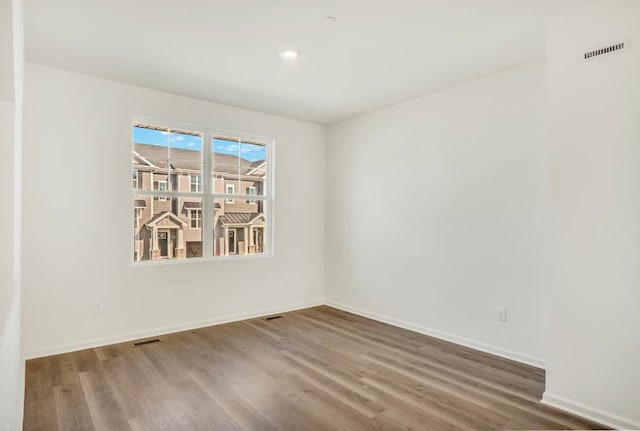 spare room with visible vents, baseboards, and wood finished floors