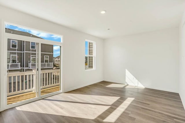 empty room with wood finished floors, baseboards, and recessed lighting