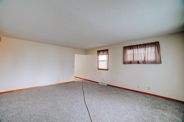 carpeted empty room with baseboards and a textured ceiling