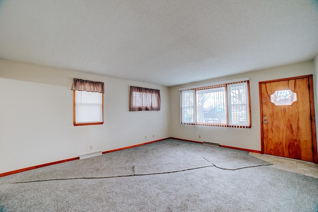 carpeted empty room featuring baseboards, a textured ceiling, and visible vents