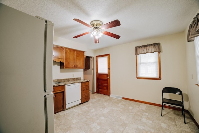 kitchen with white appliances, baseboards, visible vents, ceiling fan, and brown cabinets
