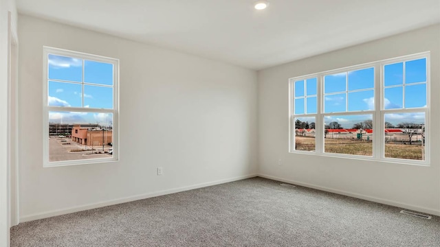 unfurnished room with visible vents, baseboards, plenty of natural light, and carpet floors