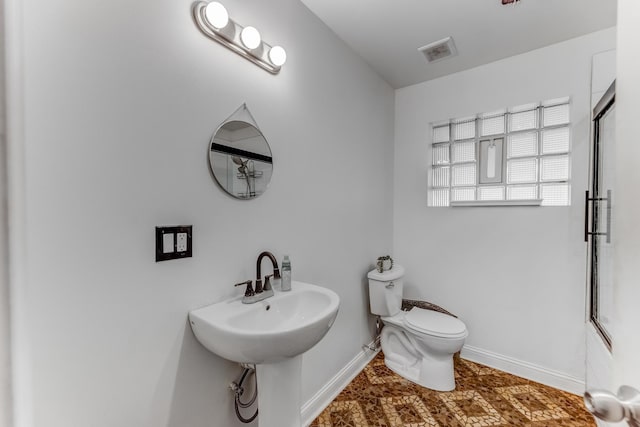 full bathroom with toilet, a shower with shower door, baseboards, and visible vents