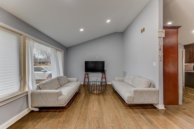 living area with visible vents, baseboards, vaulted ceiling, and wood finished floors