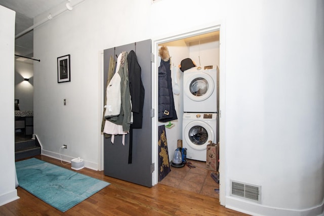 laundry area featuring visible vents, laundry area, stacked washing maching and dryer, and wood finished floors