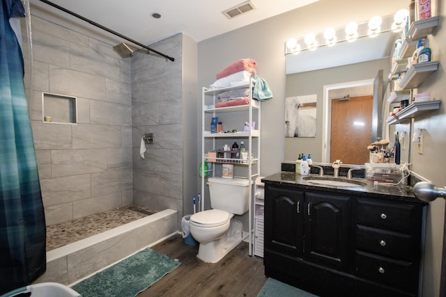 full bath with vanity, toilet, a shower stall, wood finished floors, and visible vents