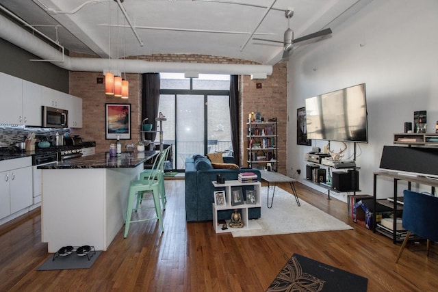 living room featuring ceiling fan, a wall of windows, and dark wood-style floors