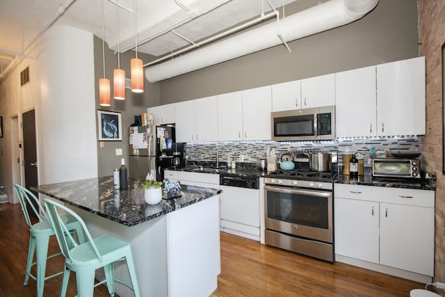 kitchen with a sink, tasteful backsplash, stainless steel appliances, and dark wood finished floors