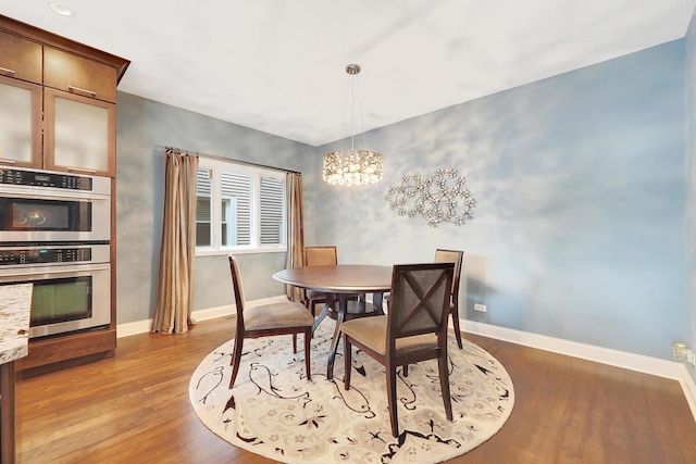 dining space with baseboards, a chandelier, and wood finished floors