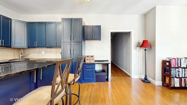 5110 S Woodlawn Ave Unit 2H, Chicago, IL 60615 - kitchen with light wood-type flooring, blue cabinetry, backsplash, dark stone counters, and a sink