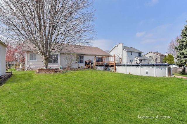 rear view of property with a yard, a deck, fence, and an outdoor pool
