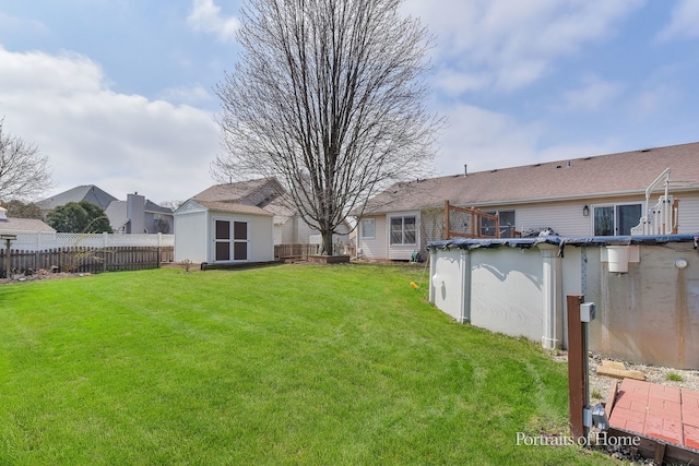 view of yard with fence, an outbuilding, a shed, and a fenced in pool