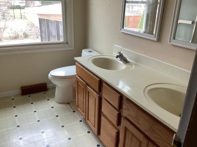 full bathroom featuring double vanity, a sink, and toilet