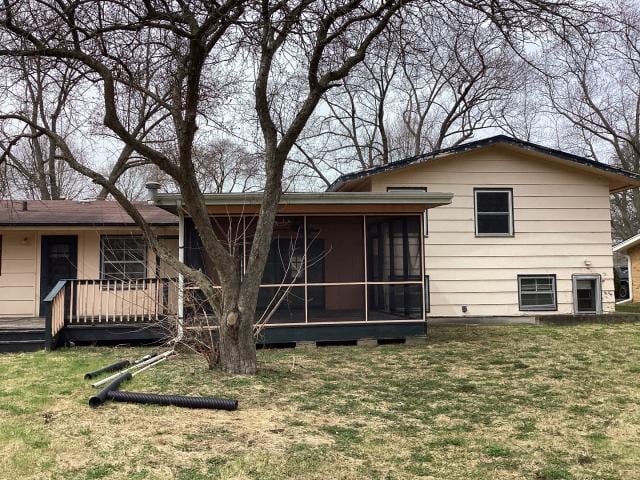 rear view of property featuring a sunroom and a yard