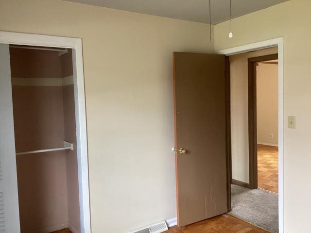 unfurnished bedroom with carpet floors, baseboards, and visible vents